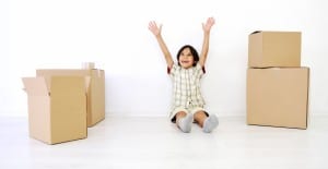 Little boy in a room of moving boxes with hands up